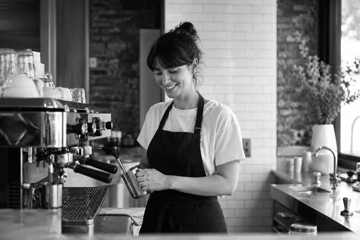 Australian café owner preparing coffee at a stainless espresso machine.